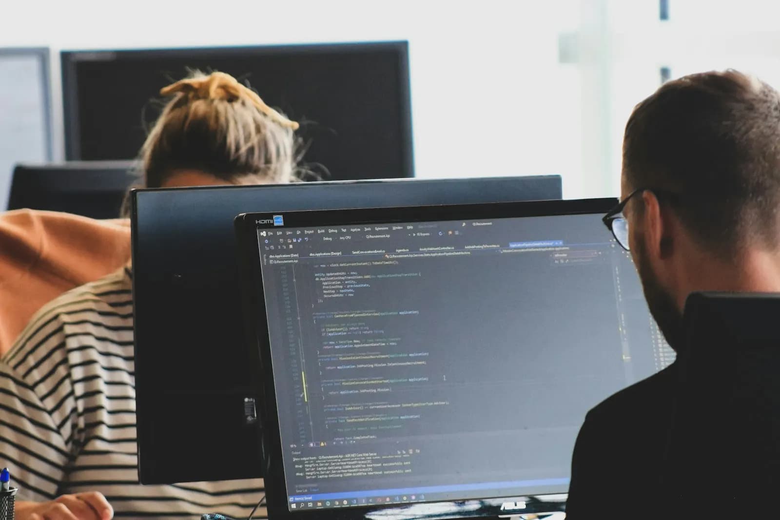 Two developers pairing at monitors, aligning on a shared architecture