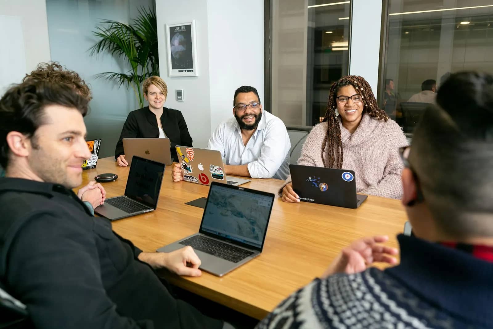 Diverse engineering team smiling in a meeting around laptops